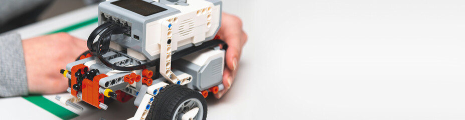 Teen student with diy robot on stem education class.Fixing mechanic toy car.Teen scientist working on new project.Stem education Learning To Program Robot Vehicle.Banner.