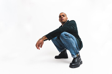 Serious focused male model squatting in studio during fashion photoshoot. Full-length shot over...