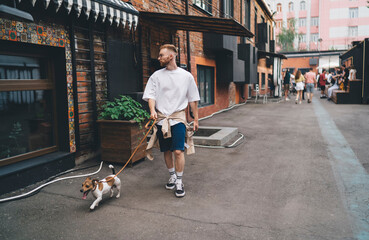 Stylish guy walking with dog down street