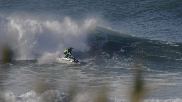 A jet ski rider rides a wave and then gets catapulted into the air to perform a spin trick