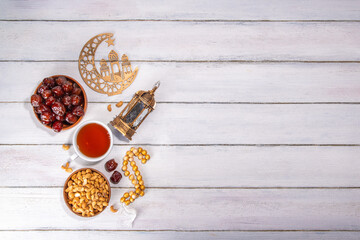 Ramadan muslim holiday background, with traditional treats - dates, nuts, dried fruits, sweets, religion rosary beads, lantern, tea, islamic Mosque, crescent moon Ramadan Kareem themed decorations