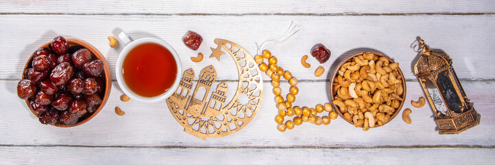 Ramadan muslim holiday background, with traditional treats - dates, nuts, dried fruits, sweets, religion rosary beads, lantern, tea, islamic Mosque, crescent moon Ramadan Kareem themed decorations