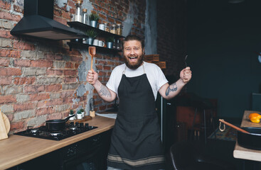 Smiling male chef with utensils in modern kitchen