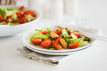 Fresh salad with mussels and tomatoes on white wooden table