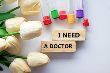 TEXT I NEED A DOCTOR and medical test tubes with flowers on a white background
