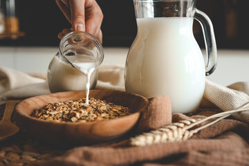 Aesthetic breakfast. Milk jug pouring milk into the bowl with natural muesli made from mix of...