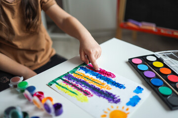 Fototapeta premium The child draws flowers. Ideas for drawing with finger paints. Finger painting for kids on white background. Little girl painting by finger hand paint color. Children development concept