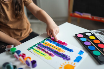 The child draws flowers. Ideas for drawing with finger paints. Finger painting for kids on white background. Little girl painting by finger hand paint color. Children development concept