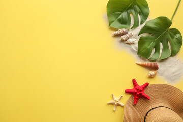 Hat, sand, seashells on a yellow summer background, space for text