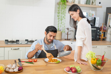 Happy young couple cooking together in the kitchen at home