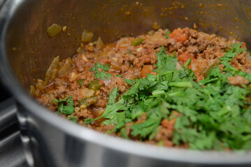 Ground meat in the pan with vegetables, green onion, onion, coriander and tomato, cooks day , chefs day