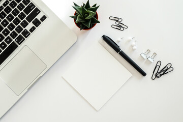 White office desk table with blank notebook, computer keyboard and other office supplies. Top view with copy space, flat lay.