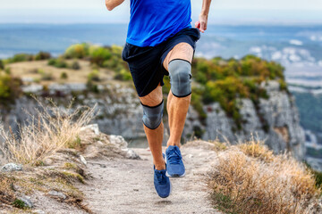 legs runner man in knee pads running mountain trail, protection knee sleeve after injury to...