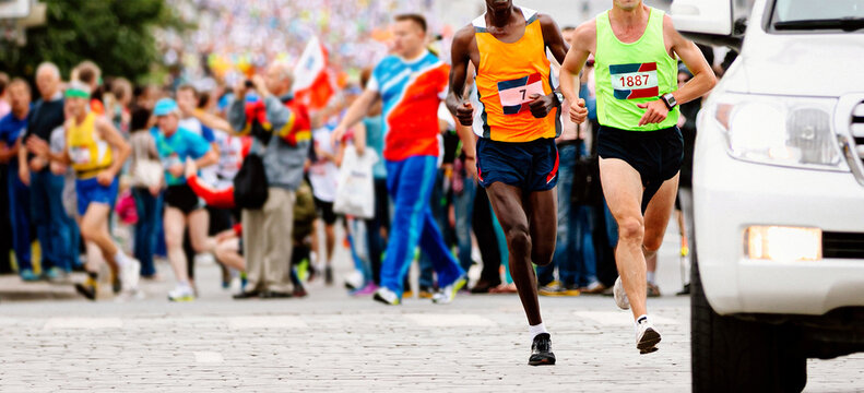 two leading runners kenyan and european running marathon behind an escort car, jogger run world championships race