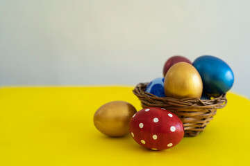 Easter eggs in basket and near in a yellow background, Easter template and concept Selective focus