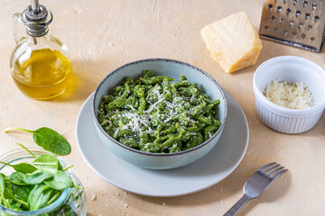 Spinach spatzle (or green spatzle) are the typical Tyrolean green dumplings or gnocchi on plate with grated cheese and olive oil