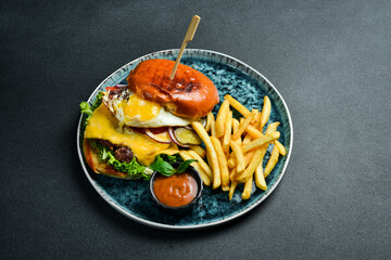 Cheeseburger with cutlet and fried egg. On a dark background, close-up.