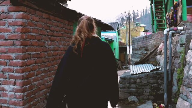 Woman walking through a narrow alley in a remote village in the Indian Himalayas - Tosh, Parvati Valley -  Himachal Pradesh, Northern India