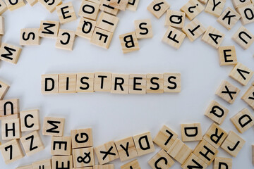 close-up holds wooden alphabet blocks on white background, changes word stress to distress, concept...