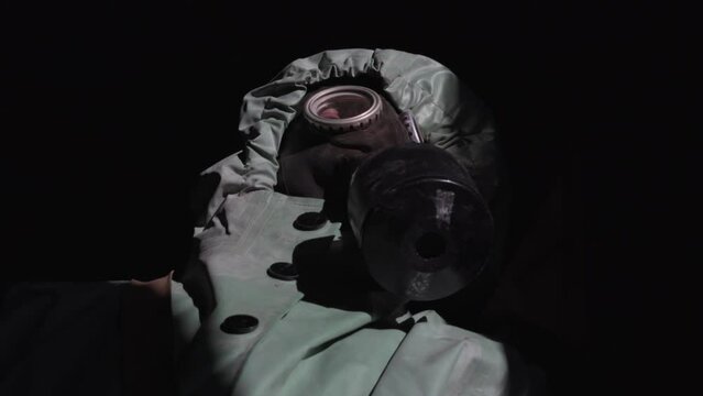 Specialist wearing respirator checks for radiation with devices in empty dark garage. Man worker attempts to find source of radiation