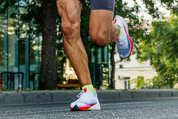 close-up legs male runner running city marathon race, athlete jogging on asphalt road, summer...