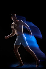 Photo of young handsome male body glowing neon light over dark background. Mixed neon light