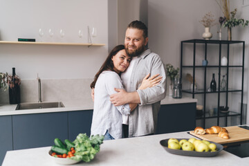 Caring couple hugging and smiling in kitchen