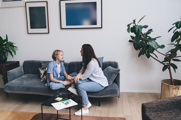 Content woman and boy talking to each other on sofa