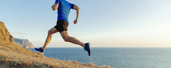 male runner running mountain sea trail on withered grass, cross-country running race
