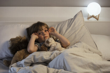 The child was scared before going to bed. Night terrors in a child. The kid covers his face with...