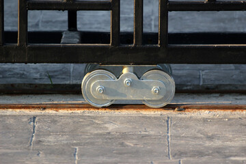 Shiny new metal gate rollers. Gate wheels for wrought iron gate of a driveway of a residential...