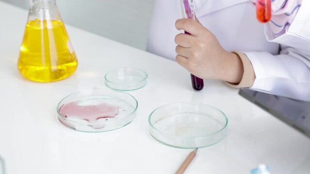 Hand of Elementary schoolgirls with gown uniform scientist imagination having fun with experiment, sibling kids workshop study in laboratory lab, modern lifestyle kids science education concept
