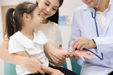 Fototapeta premium The doctor held the young patient's hand, and the mother smiled and encouraged her.