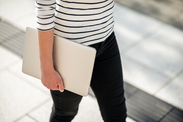 Woman walking and carrying a laptop