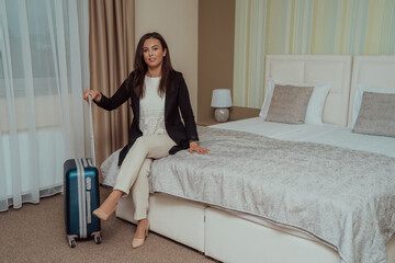 The woman is sitting on the bed while resting from the tiring journey