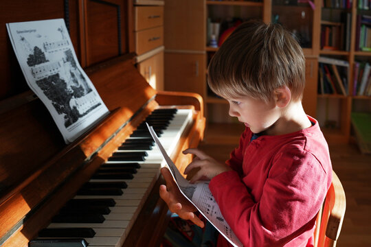 Adorable cute caucasian little toddler boy having playing piano at home. Education, child development concept. Selective focus. - Powered by Adobe