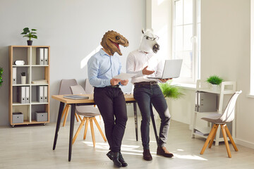 Animal people using laptop in office workplace. Team of 2 business men in unusual funny masquerade...