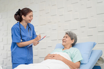 Obraz premium A female nurse or doctor is caring for an elderly female patient lying on the patient's bed doing heart and breathing tests. and the patient has a smile