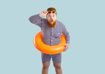 Funny surprised fat man in beach floatie standing isolated on blue background. Plump man in...