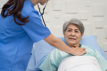 Obraz premium A female nurse or doctor is caring for an elderly female patient lying on the patient's bed doing heart and breathing tests. and the patient has a smile