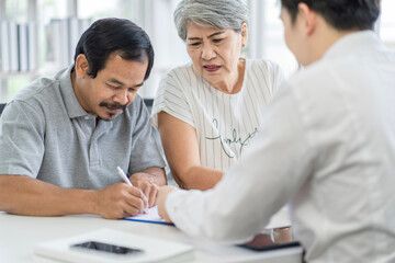 Obraz premium Asian seniors who are healthy, in a good mood, smiling, talking with financial or life insurance staff to take care of life after retirement.