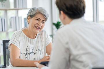 Obraz premium Asian seniors who are healthy, in a good mood, smiling, talking with financial or life insurance staff to take care of life after retirement.