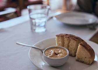 Pea pate with garlic in a small ceramic bowl with pieces of a bun on a white ceramic  plate.