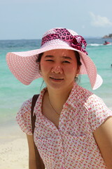 Portrait of young asian woman in pink hat on the beach.
