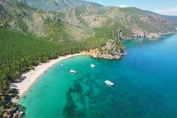 Fototapeta premium Yachts near the shore of Lake Baikal, in Babushka Bay, tourists sunbathe on a sandy beach. Beautiful summer seascape. Aerial view