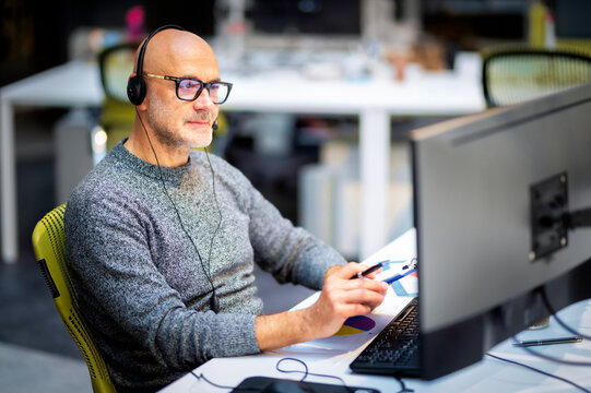 Mature businessman sitting at the table and working on computers at the office