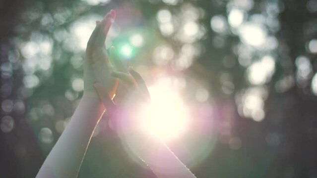 Close up girl dancing with her arms to sun against background on forest