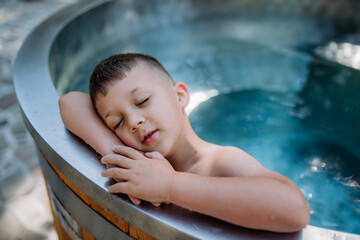 Happy little boy relaxing in outdoor hot tub. Summer holiday, vacation concept.