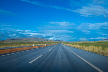 rain-soaked highway and blue sky with clouds