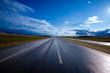 Naklejka premium rain-soaked highway and blue sky with clouds